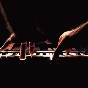 Playing a keyboard, two male hands playing, accentuated contrasts.